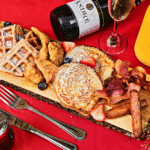 a variety of breakfast dishes are arranged on a board – from waffles and pancakes to savory sausage
